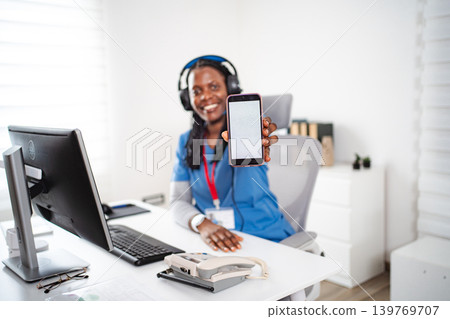 Nurse wearing headphones showing smartphone with blank screen Nurse wearing headphones showing smartphone with blank screen 139769707