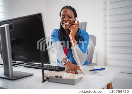 Medical professional using phone for consultation at office desk Medical professional using phone for consultation at office desk 139769710