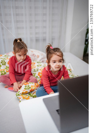 Young sisters watching laptop while sitting on bed 139769722
