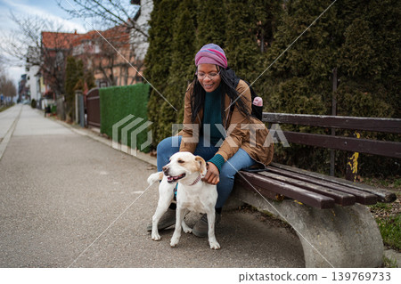 Woman petting happy dog sitting on park bench outdoors Woman petting happy dog sitting on park bench outdoors 139769733