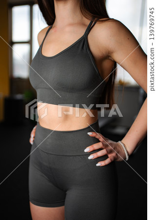 Young woman posing in grey sports bra and shorts Young woman posing in grey sports bra and shorts 139769745
