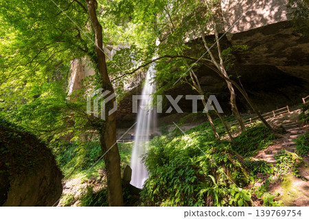 A valley enveloped in fresh greenery and a cascading waterfall – a truly picturesque scene. A valley enveloped in fresh greenery and a cascading waterfall – a truly picturesque scene. 139769754
