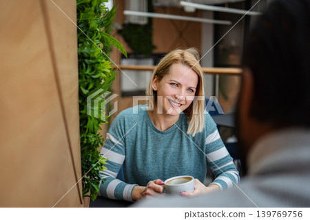 Woman smiling having coffee and conversation in cafe Woman smiling having coffee and conversation in cafe 139769756
