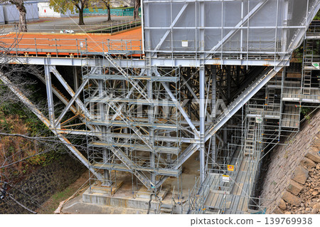 Covered facade of a reconstruction building, Scaffolding with safety nets during renovation building. Covered facade of a reconstruction building, Scaffolding with safety nets during renovation building. 139769938
