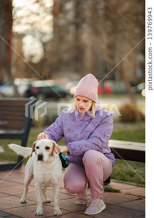 Woman petting white labrador dog outdoors in park Woman petting white labrador dog outdoors in park 139769943