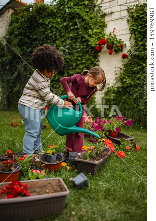 Children watering flowers in backyard garden together Children watering flowers in backyard garden together 139769981