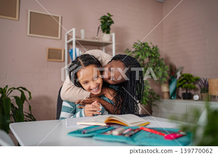 Black mother hugging daughter studying at home Black mother hugging daughter studying at home 139770062