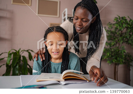 Mother helping daughter with homework while studying at home 139770063