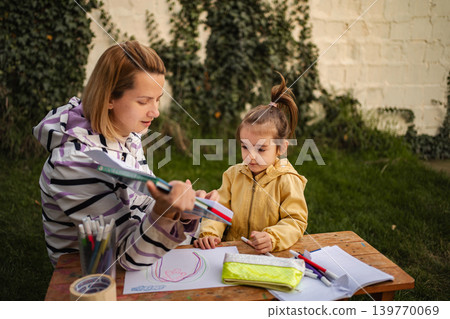Mother and daughter drawing, learning together outdoors Mother and daughter drawing, learning together outdoors 139770069