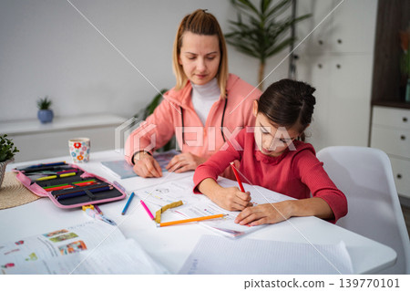 Mother and daughter learning together, doing homework at home Mother and daughter learning together, doing homework at home 139770101