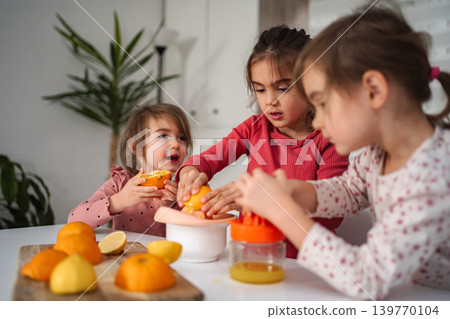 Children making fresh orange lemon juice in kitchen Children making fresh orange lemon juice in kitchen 139770104