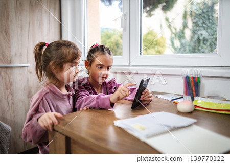 Girls watching content on smartphone together at home Girls watching content on smartphone together at home 139770122