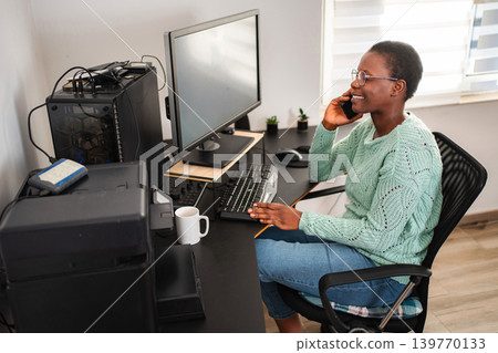 Young black woman talking on phone working from home 139770133