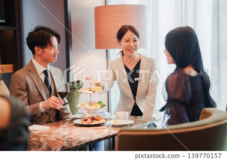 Men and women enjoying afternoon tea with staff Men and women enjoying afternoon tea with staff 139770157