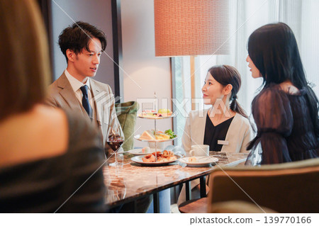 Men and women enjoying afternoon tea with staff 139770166