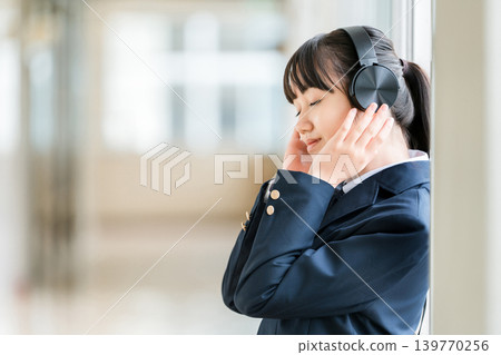 小學、國中、高中女生穿著校服在學校走廊上戴著耳機聽音樂 139770256