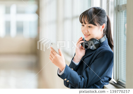 小學、國中、高中女生穿著校服在學校走廊上戴著耳機聽音樂 139770257
