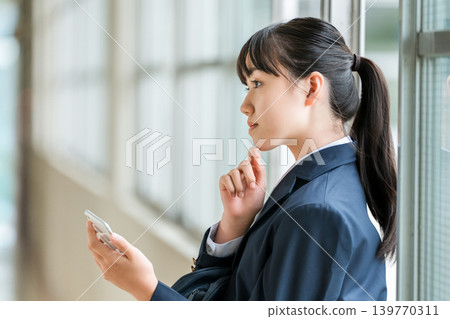 Elementary, middle, and high school girls using smartphones in the school hallway (looking depressed, thinking, worried, confused, troubled) Elementary, middle, and high school girls using smartphones in the school hallway (looking depressed, thinking, worried, confused, troubled) 139770311