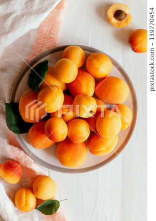 Delicious ripe organic apricots on a white plate and wooden table. Delicious ripe organic apricots on a white plate and wooden table. 139770454