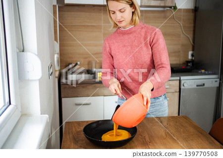 Woman pouring mixture into pan preparing healthy homemade meal Woman pouring mixture into pan preparing healthy homemade meal 139770508