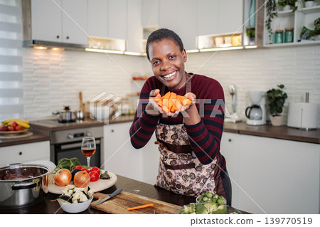 Woman holding chopped carrots in modern kitchen enjoying cooking 139770519