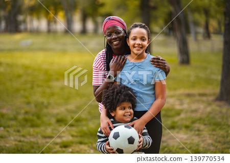African American mother and happy children playing soccer outdoors African American mother and happy children playing soccer outdoors 139770534