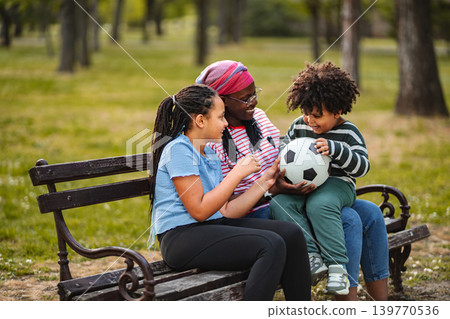 Family parents and children playing with a soccer ball in park 139770536