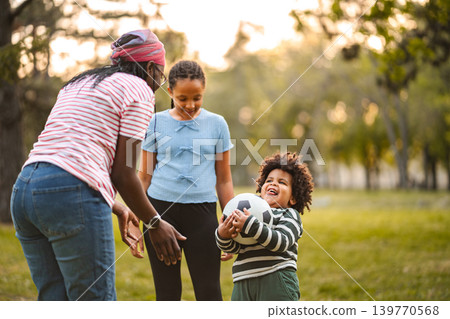 Family playing soccer outdoors with children in park Family playing soccer outdoors with children in park 139770568