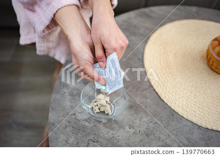 Woman pouring a cosmetic product into a bowl, preparing a homemade beauty treatment Woman pouring a cosmetic product into a bowl, preparing a homemade beauty treatment 139770663