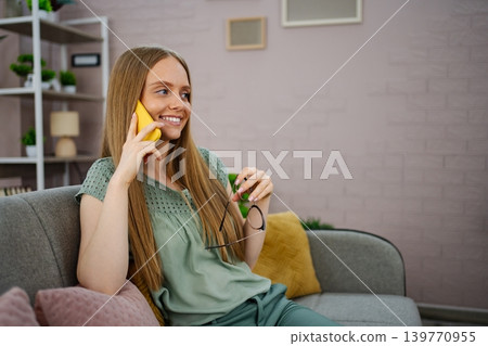 Woman with long hair chats happily on her phone in a bright space Woman with long hair chats happily on her phone in a bright space 139770955