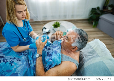 Caring nurse helps elderly man take his medicine at home Caring nurse helps elderly man take his medicine at home 139770967