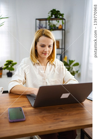 Woman working intently on a laptop in a bright room 139770968