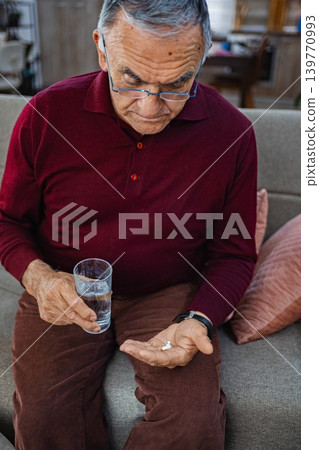 Elderly man preparing to take medication with water Elderly man preparing to take medication with water 139770993