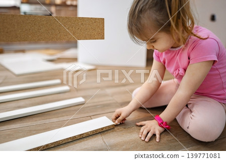 Child engaged in playful construction with wooden pieces indoors Child engaged in playful construction with wooden pieces indoors 139771081