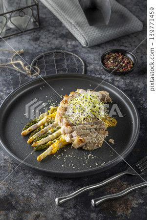 Sliced pork tenderloin with grilled asparagus and cheese sauce, garnished with microgreens Sliced pork tenderloin with grilled asparagus and cheese sauce, garnished with microgreens 139771459