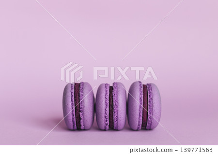 Three french macarons on a purple background. Place for text. Three french macarons on a purple background. Place for text. 139771563