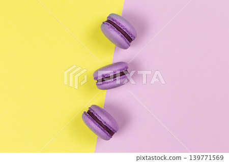 Three purple french macarons on a yellow and purple background. Three purple french macarons on a yellow and purple background. 139771569