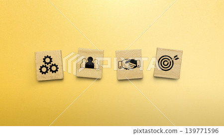 Four square blocks with business icons representing teamwork, strategy, partnership, and goals on a vibrant yellow background Four square blocks with business icons representing teamwork, strategy, partnership, and goals on a vibrant yellow background 139771596