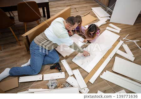 Family bonding while assembling furniture on a weekend afternoon Family bonding while assembling furniture on a weekend afternoon 139771636