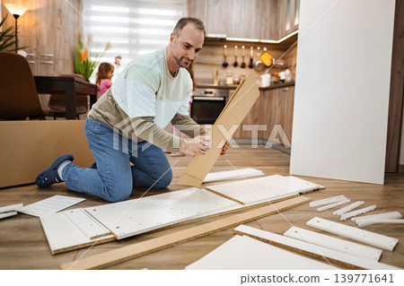 Man assembling furniture in a cozy kitchen during family time Man assembling furniture in a cozy kitchen during family time 139771641
