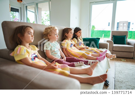 Children relaxing on a couch in a cozy living room Children relaxing on a couch in a cozy living room 139771714