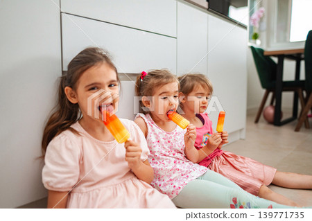 Three girls enjoying colorful popsicles on a warm day Three girls enjoying colorful popsicles on a warm day 139771735