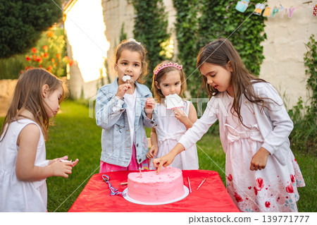 Kids enjoy cake at a joyful outdoor party Kids enjoy cake at a joyful outdoor party 139771777