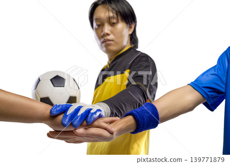 A Indonesian southeast asian goalkeeper and teammates joining hands in a stack to show unity and team spirit before a soccer match. Isolated on a white background showing sportsmanship A Indonesian southeast asian goalkeeper and teammates joining hands in a stack to show unity and team spirit before a soccer match. Isolated on a white background showing sportsmanship 139771879