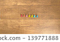 七個小巧多彩的夾子整齊地排列在木紋背景前。 139771888