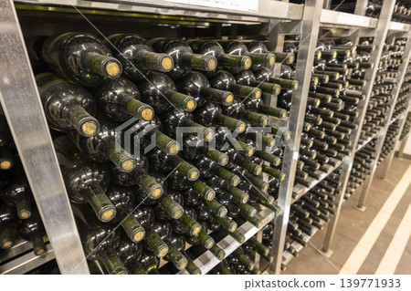 Wine bottles aging on metal shelves in cellar with tiled floor Wine bottles aging on metal shelves in cellar with tiled floor 139771933