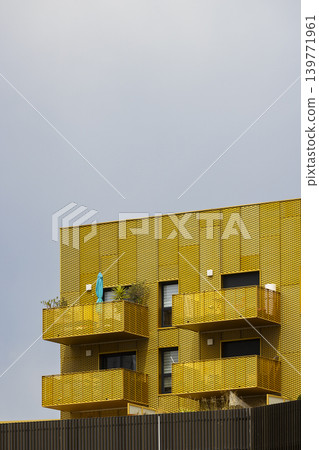 Yellow facade of a modern residential building with balconies and a cloudy sky Yellow facade of a modern residential building with balconies and a cloudy sky 139771961