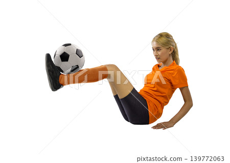 Indonesian southeast asian female athlete wearing an orange jersey and black shorts sits on the ground, balancing a soccer ball on her foot. Professional studio shot isolated on a white background Indonesian southeast asian female athlete wearing an orange jersey and black shorts sits on the ground, balancing a soccer ball on her foot. Professional studio shot isolated on a white background 139772063