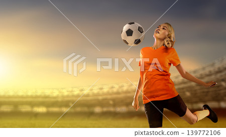 Young Indonesian southeast asian female soccer player in an orange jersey practicing ball control in a large stadium during a vibrant sunset, capturing athletic skill and focus Young Indonesian southeast asian female soccer player in an orange jersey practicing ball control in a large stadium during a vibrant sunset, capturing athletic skill and focus 139772106