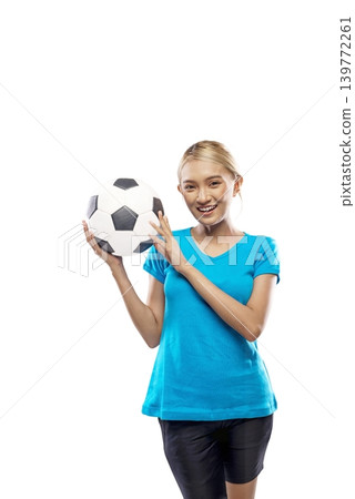 A beautiful young Indonesian southeast asian woman with blonde hair, wearing a blue t-shirt, poses while holding a classic black and white soccer ball near her face against a plain white background 139772261